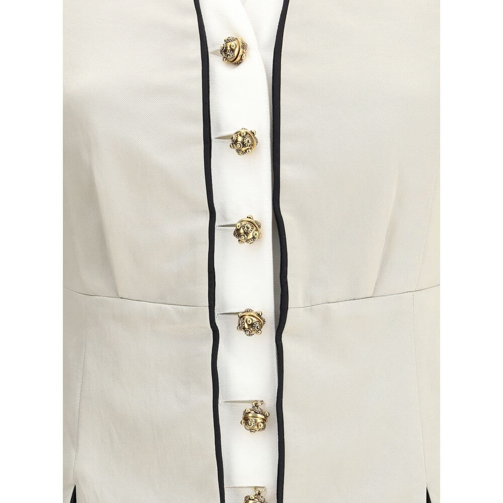 Silver Silk CoatThe Tailored Silk Jacket by Chloé reimagines classic elegance with refined details and a strong architectural touch. Its deep V-neckline is layered with a contrasting white placket, accentuated by gold-tone floral buttons for a luminous fi
