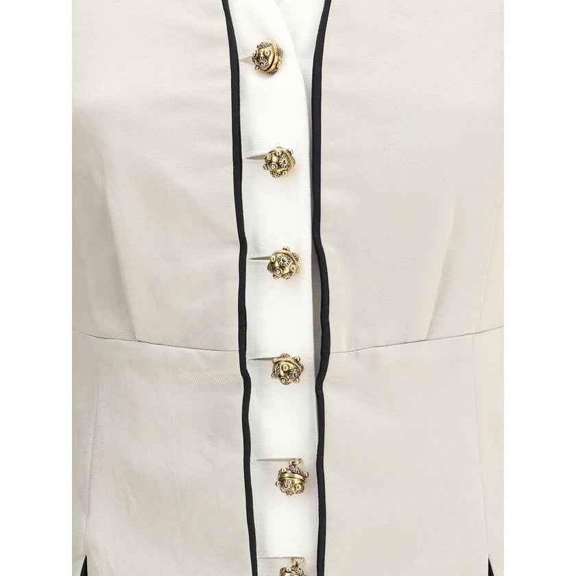 Silver Silk CoatThe Tailored Silk Jacket by Chloé reimagines classic elegance with refined details and a strong architectural touch. Its deep V-neckline is layered with a contrasting white placket, accentuated by gold-tone floral buttons for a luminous fi