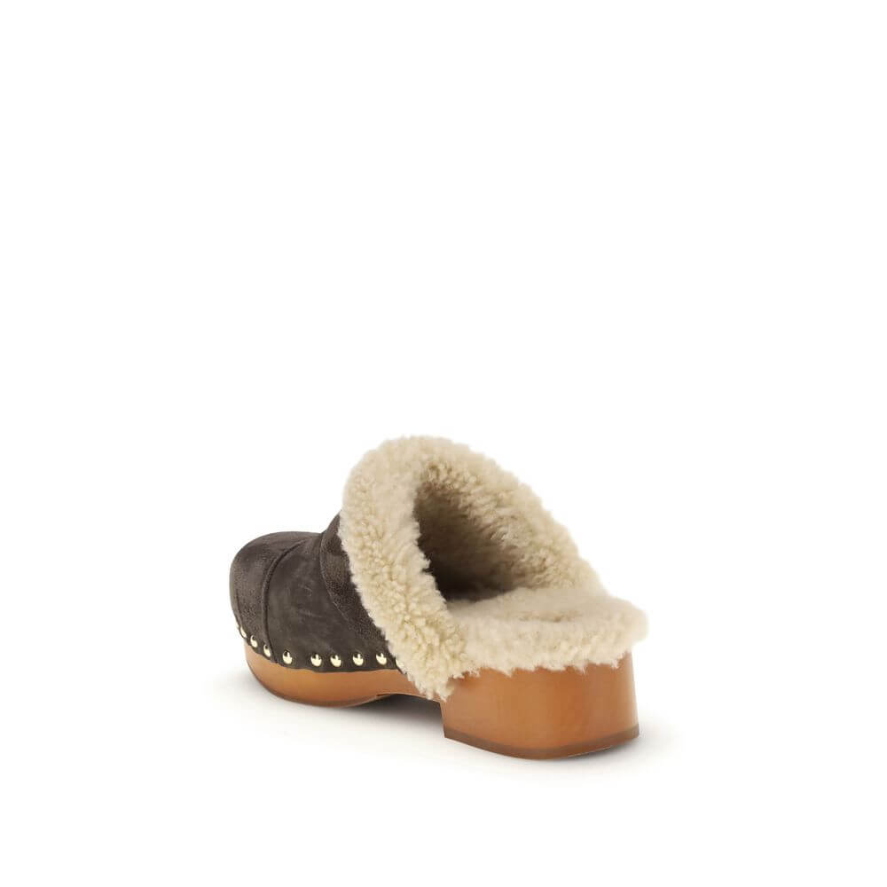 Brown Fur ClogsThe Jeannette Clogs by Chloé are crafted from suede and lined with soft shearling for warm, cozy comfort. They are embellished with gold-tone studs and buckles shaped like the brand’s initial. The wooden sole and suede upper combine traditi
