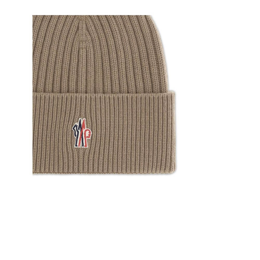 Beige Merino Wool BeanieBeanie Hat by Moncler Grenoble combines functionality and style in an essential cold-weather accessory. Made with ribbed fabrication, it offers a snug and comfortable fit. The Moncler Grenoble logo sewn on the front adds a distinct