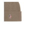 Beige Merino Wool BeanieBeanie Hat by Moncler Grenoble combines functionality and style in an essential cold-weather accessory. Made with ribbed fabrication, it offers a snug and comfortable fit. The Moncler Grenoble logo sewn on the front adds a distinct