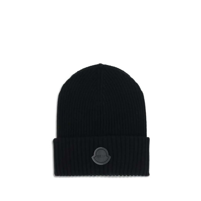 Black Wool BeanieThe Hat by Moncler x Edward Enninful is crafted from virgin wool. Featuring a ribbed knit, folded brim, and a front logo patch, it’s an essential and distinctive accessory. The unlined construction ensures a lightweight and comfortable fi