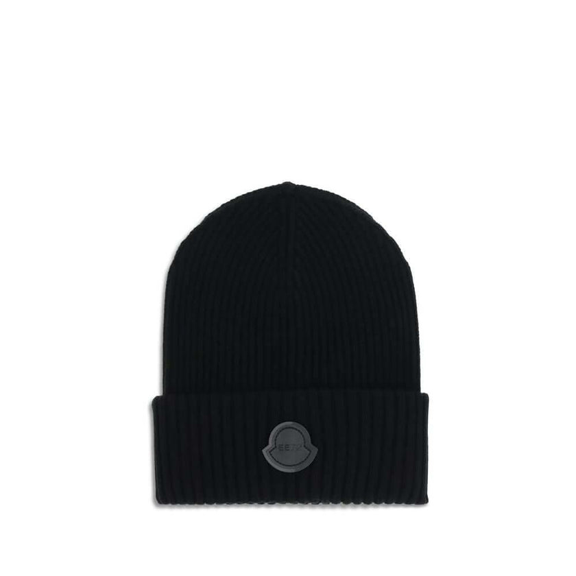 Black Wool BeanieThe Hat by Moncler x Edward Enninful is crafted from virgin wool. Featuring a ribbed knit, folded brim, and a front logo patch, it’s an essential and distinctive accessory. The unlined construction ensures a lightweight and comfortable fi