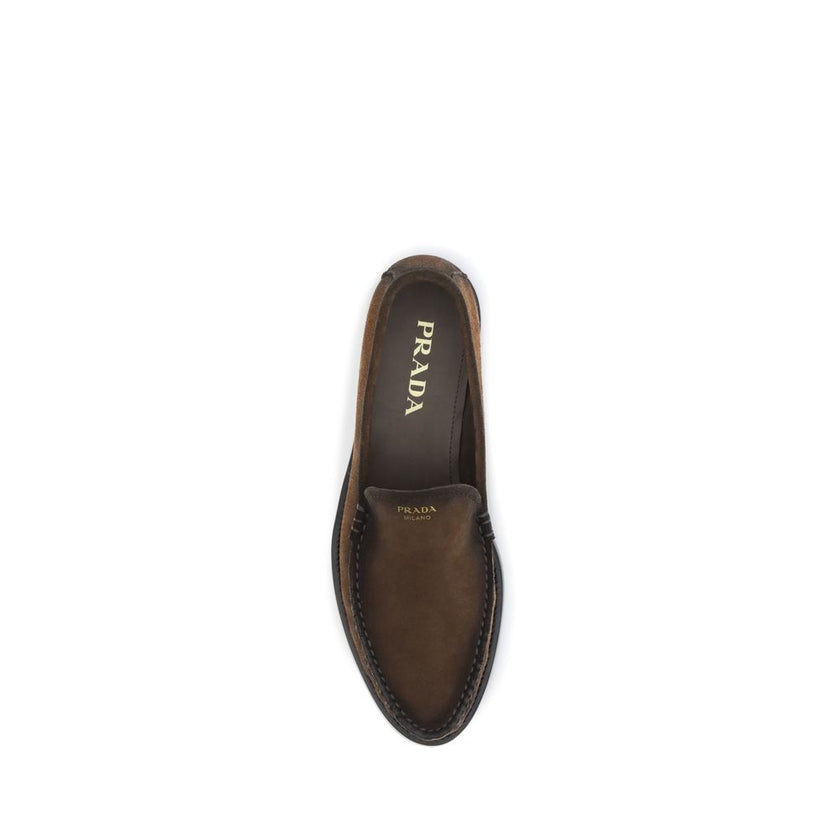 Brown Leather Slip-On LoafersThe Loafers by Prada crafted from vintage-effect suede leather, featuring a laminated logo printed on the vamp. Designed with a rounded toe and an internal printed logo, they express a timeless and elegant aesthetic. Season: A